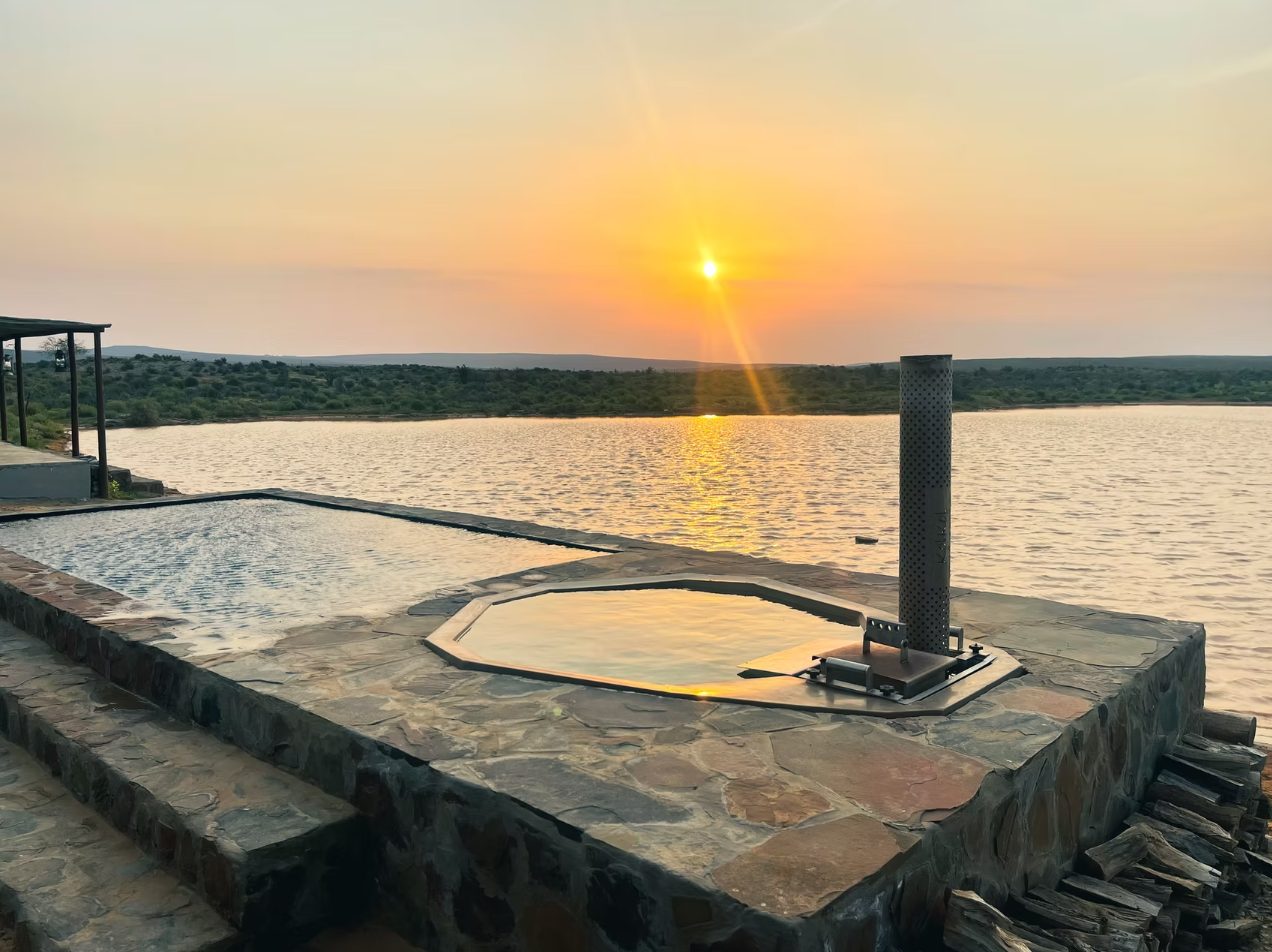 Wood-fired hot tub beside the infinity pool at Doringbos, sunset over the Doring River